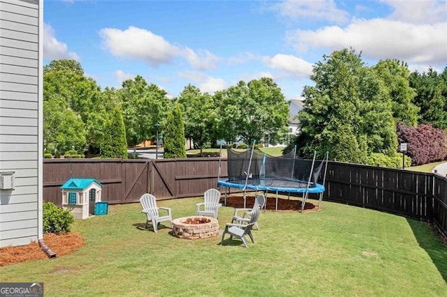 view of yard with an outdoor fire pit and a trampoline