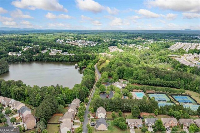 aerial view of property's location featuring a large body of water, a heavily wooded area, and nearby suburban area
