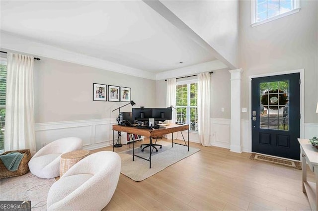 office area with light wood-style flooring, a wainscoted wall, and a decorative wall