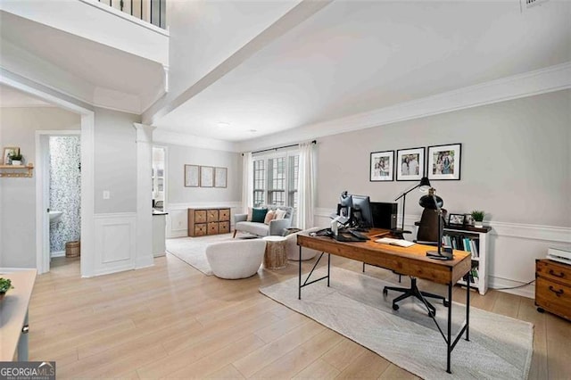 office featuring light wood-type flooring, decorative columns, a wainscoted wall, a decorative wall, and crown molding
