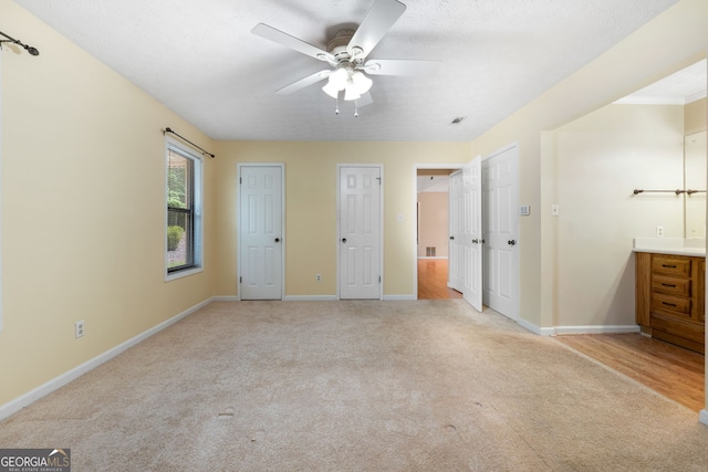 unfurnished bedroom featuring light carpet, two closets, baseboards, and a ceiling fan