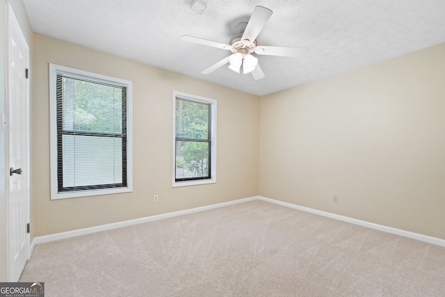 spare room with healthy amount of natural light, baseboards, light colored carpet, and a textured ceiling