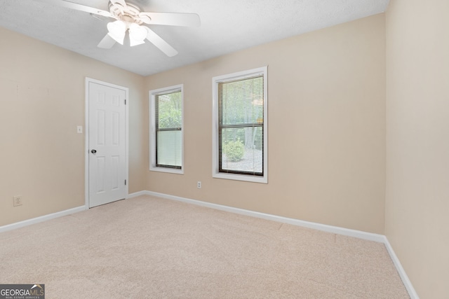 empty room featuring light carpet, ceiling fan, and baseboards