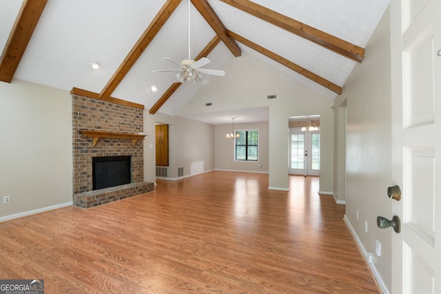unfurnished living room with beam ceiling, light wood-style flooring, a chandelier, ceiling fan, and high vaulted ceiling