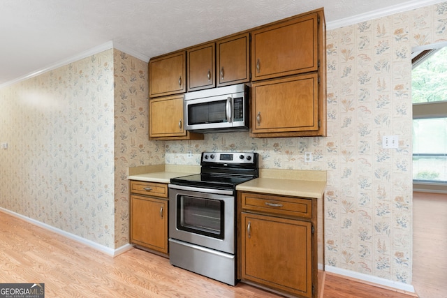 kitchen featuring stainless steel appliances, light wood-style flooring, light countertops, plenty of natural light, and ornamental molding