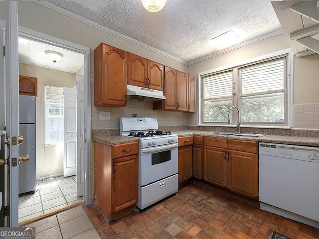 6296 Longino Dr, Union City, GA 30291 - kitchen with white appliances, under cabinet range hood, a sink, brown cabinetry, and crown molding