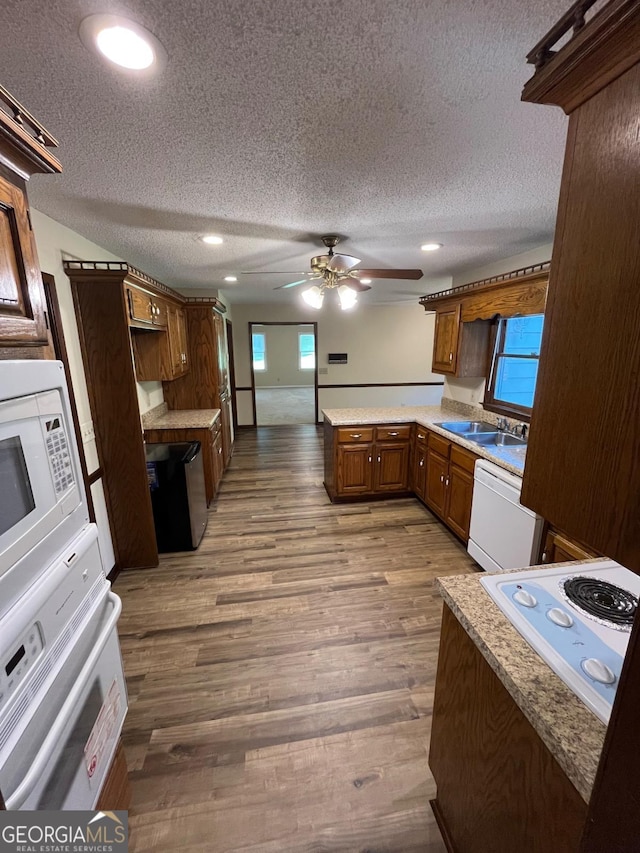 kitchen featuring white appliances, a textured ceiling, a peninsula, ceiling fan, and wood finished floors