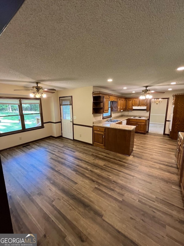 kitchen with a textured ceiling, a peninsula, a ceiling fan, brown cabinetry, and open shelves