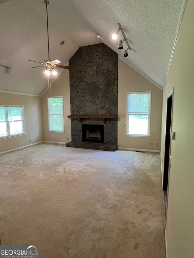 unfurnished living room featuring baseboards, vaulted ceiling, a ceiling fan, a stone fireplace, and carpet