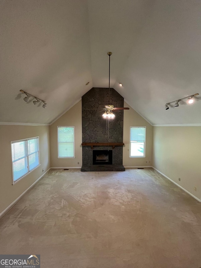 unfurnished living room with ceiling fan, baseboards, lofted ceiling, carpet floors, and a stone fireplace