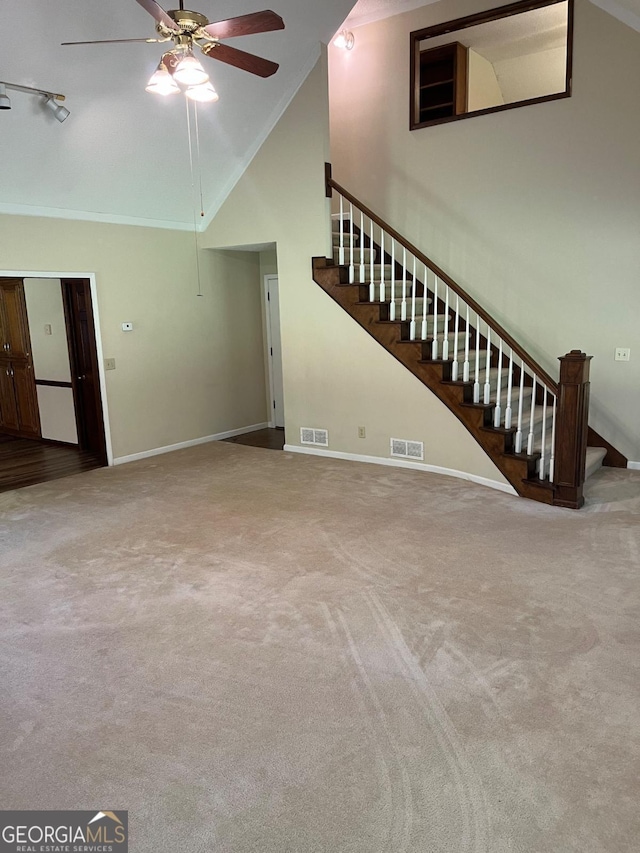 unfurnished living room with stairs, high vaulted ceiling, ceiling fan, baseboards, and carpet