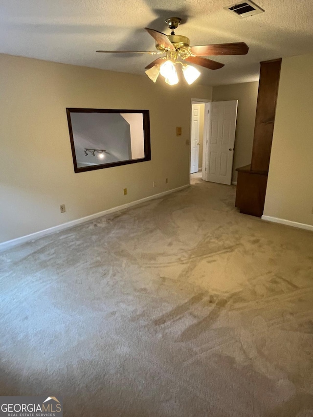 spare room with ceiling fan, carpet, baseboards, and a textured ceiling