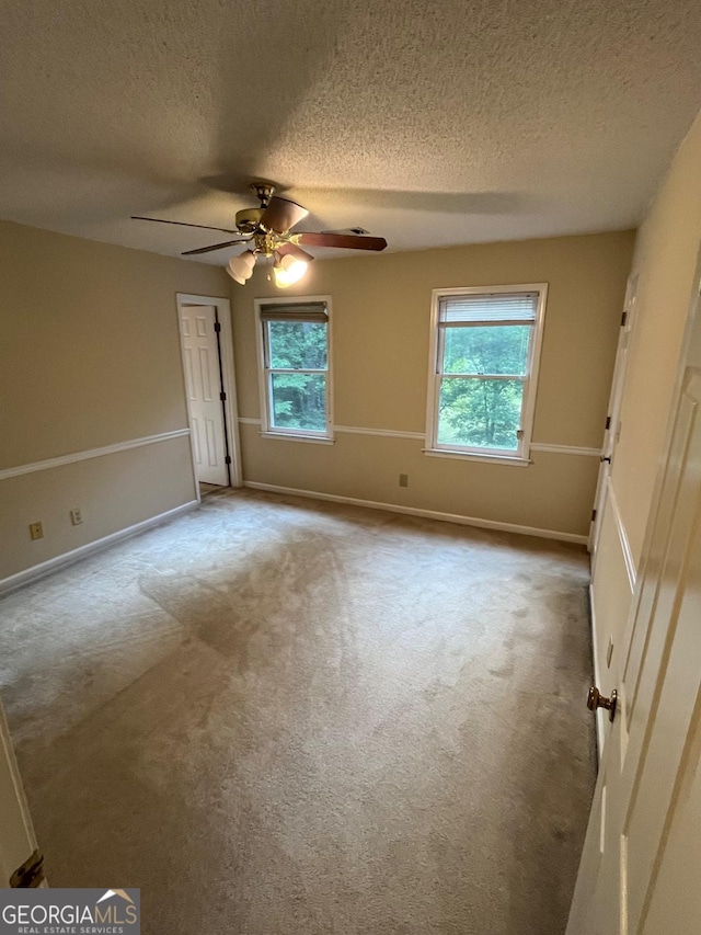 unfurnished bedroom featuring a textured ceiling, carpet, baseboards, and a ceiling fan