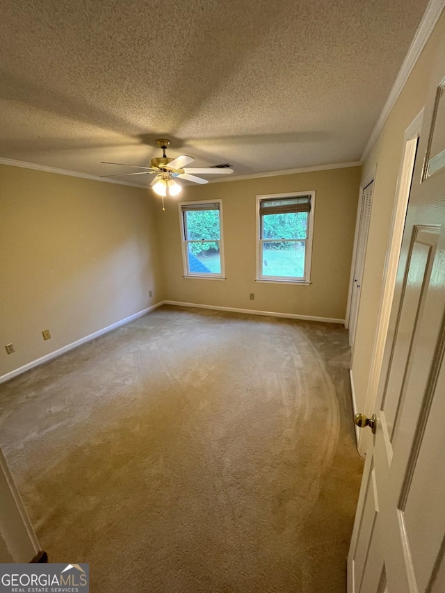 unfurnished bedroom featuring carpet floors, crown molding, a textured ceiling, baseboards, and a ceiling fan