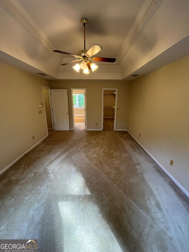 unfurnished bedroom with a tray ceiling, carpet flooring, and baseboards