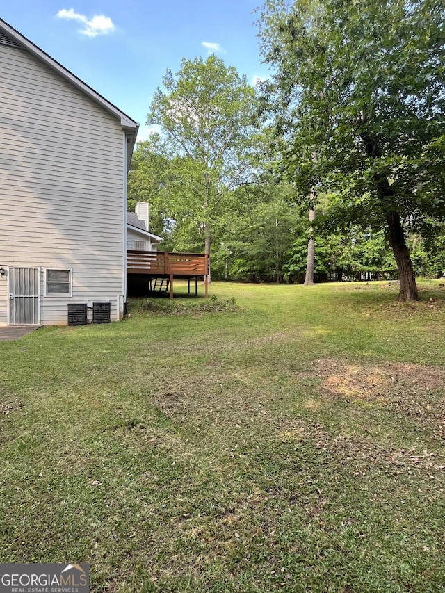 view of grassy yard with a wooden deck and central AC unit