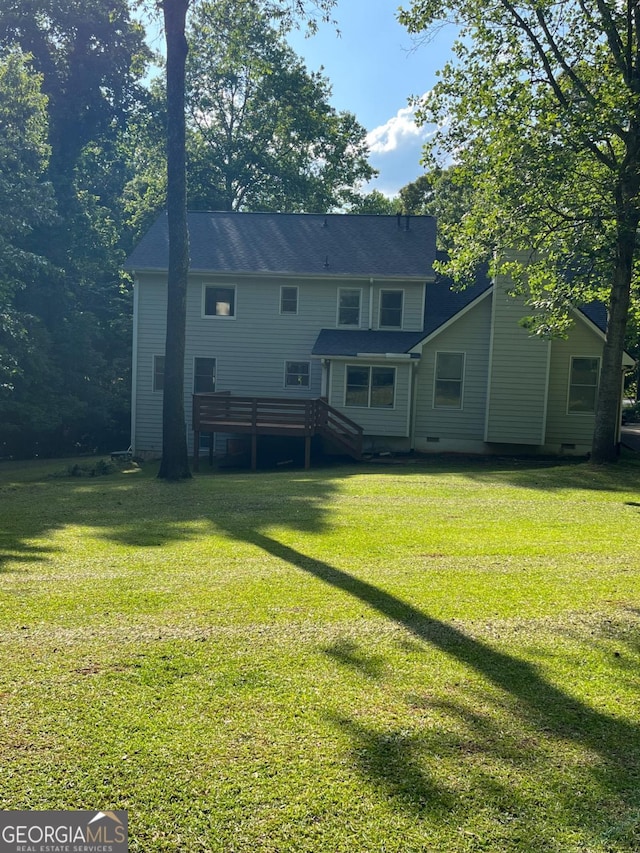 back of house featuring a lawn and a deck