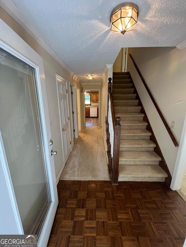 stairs featuring a textured ceiling, baseboards, and crown molding