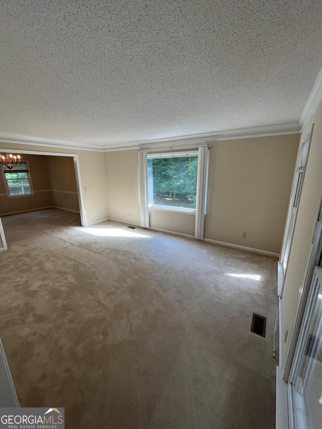 carpeted empty room featuring a textured ceiling, crown molding, plenty of natural light, a chandelier, and baseboards