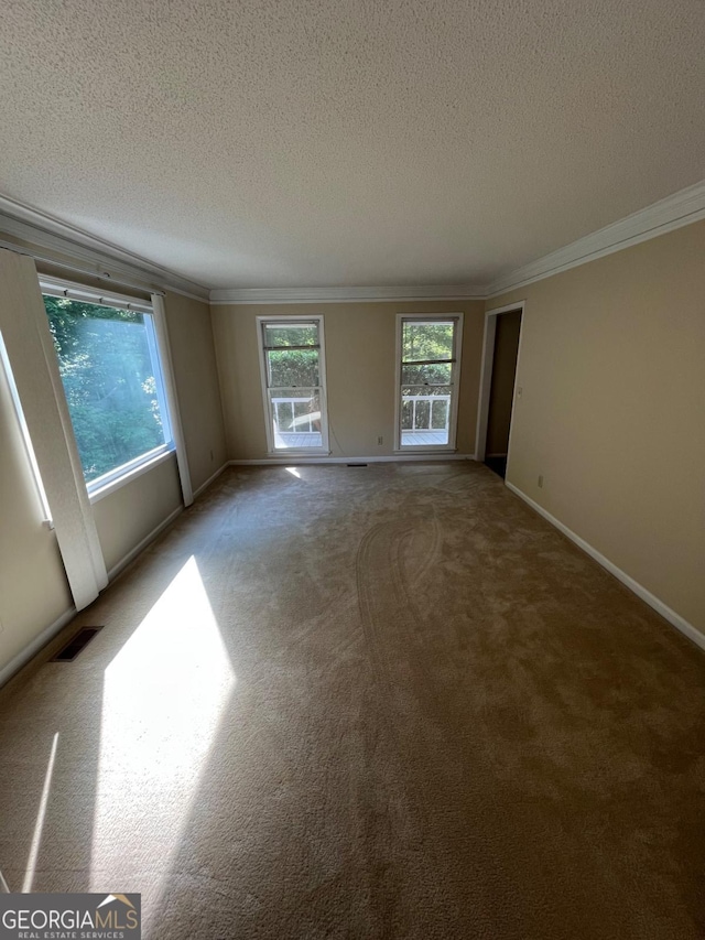 empty room with ornamental molding, a textured ceiling, light carpet, and baseboards
