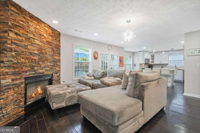 4125 Fallbrook Dr, Duluth, GA 30096 - living room featuring dark wood-style flooring, a chandelier, recessed lighting, a fireplace, and a textured ceiling