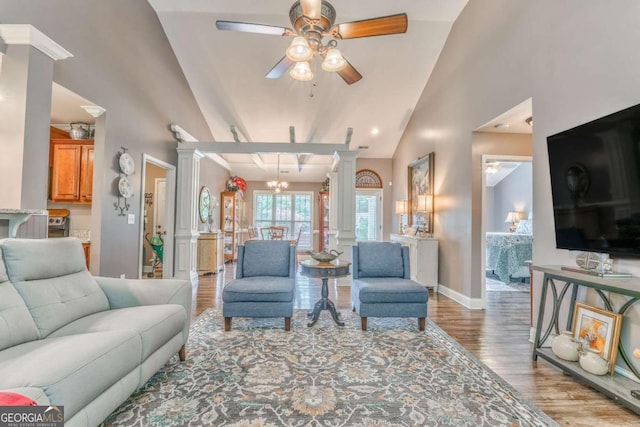 living room featuring decorative columns, vaulted ceiling, wood finished floors, ceiling fan, and baseboards