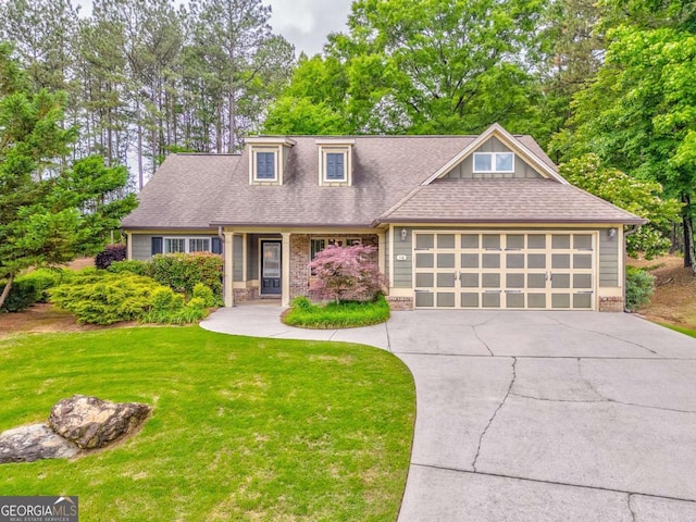 view of front of house featuring concrete driveway, a front lawn, an attached garage, a shingled roof, and view of wooded area
