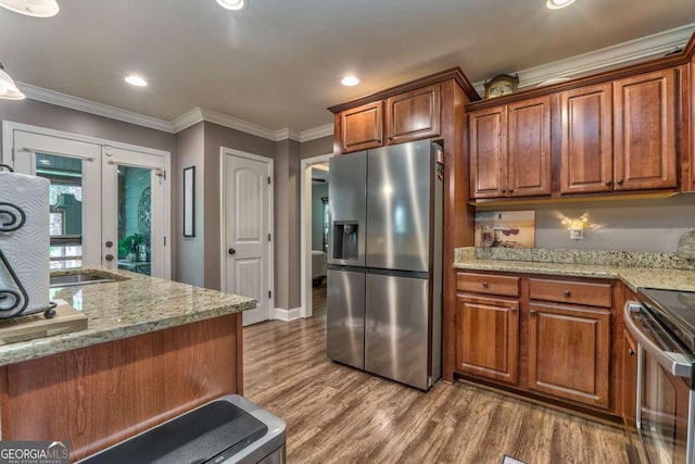 kitchen with appliances with stainless steel finishes, wood finished floors, brown cabinetry, light stone countertops, and recessed lighting