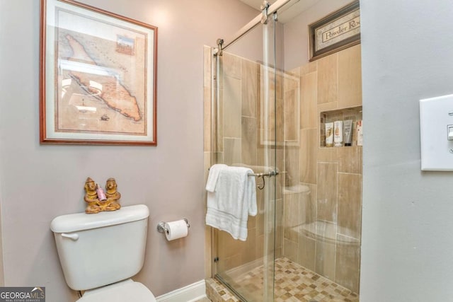 bathroom with a shower stall, toilet, and baseboards