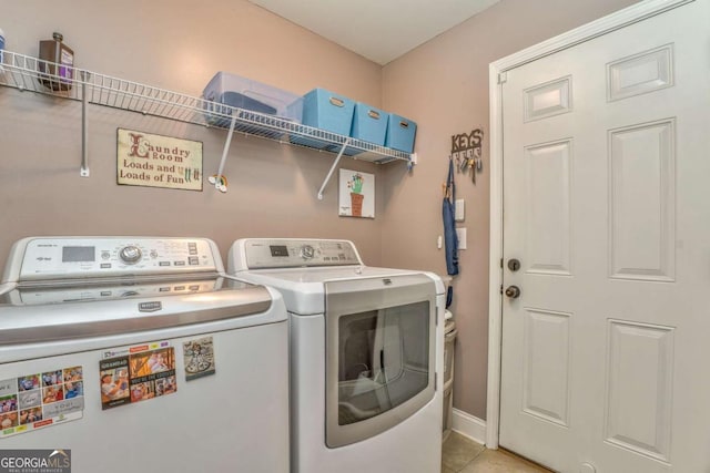 laundry area featuring washer and clothes dryer, light tile patterned floors, and baseboards