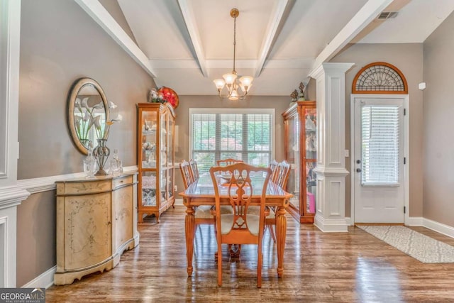 dining space with decorative columns, healthy amount of natural light, wood finished floors, beam ceiling, and a chandelier