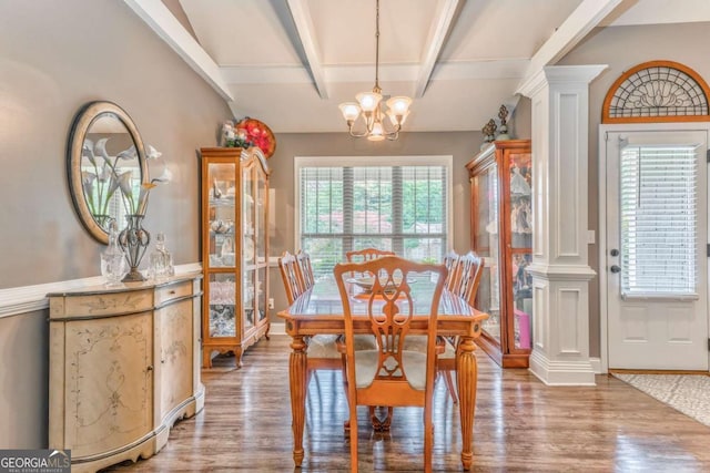 dining room with beamed ceiling, a chandelier, wood finished floors, and ornate columns