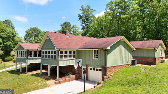 3340 Zingara Rd, Conyers, GA 30012 - view of front of house with a sunroom, a shingled roof, a chimney, an attached garage, and central air condition unit