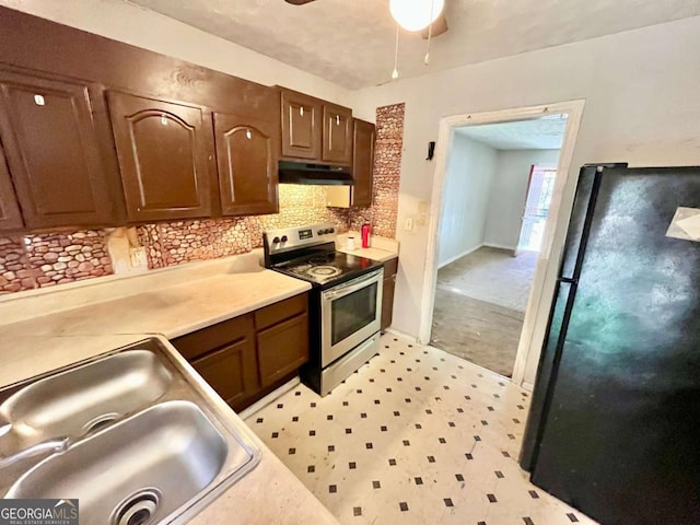 kitchen with electric stove, freestanding refrigerator, under cabinet range hood, a sink, and backsplash