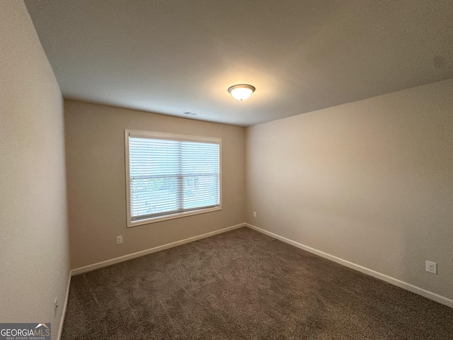 spare room with dark carpet and baseboards