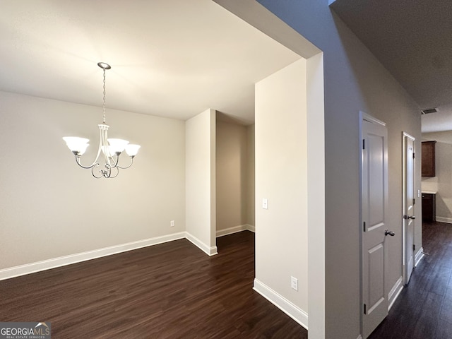 unfurnished dining area featuring dark wood-type flooring, baseboards, and a chandelier