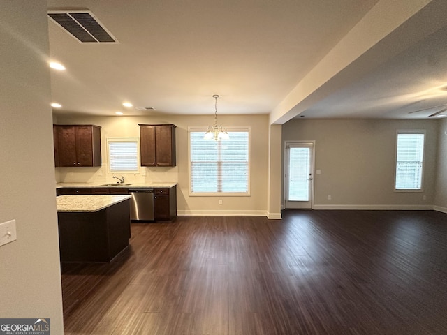 kitchen with light countertops, stainless steel dishwasher, dark brown cabinets, open floor plan, and dark wood finished floors
