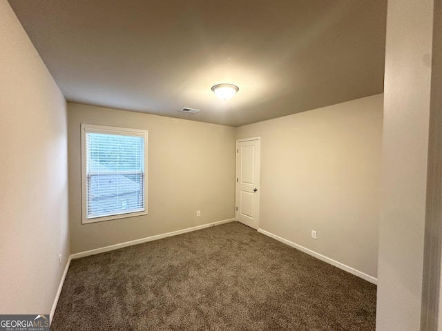 empty room with dark colored carpet and baseboards