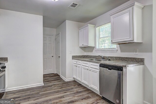 kitchen with appliances with stainless steel finishes, wood finished floors, white cabinets, baseboards, and a sink
