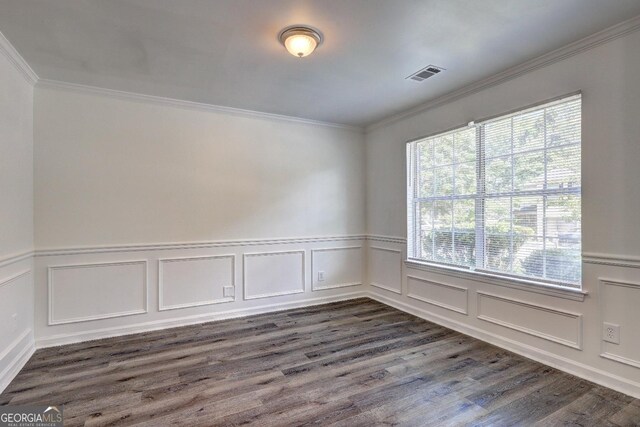 unfurnished room featuring dark wood-type flooring, crown molding, a wainscoted wall, and a decorative wall