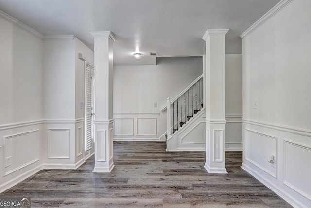 entrance foyer featuring a decorative wall, wood finished floors, stairway, a wainscoted wall, and ornate columns