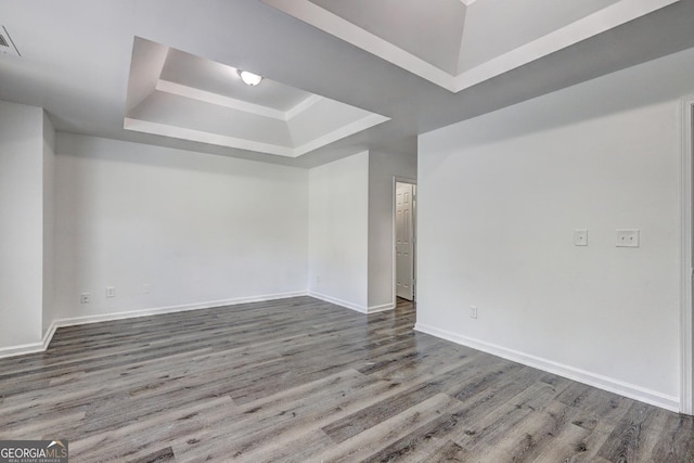 unfurnished room featuring a tray ceiling, wood finished floors, and baseboards