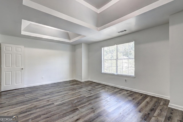 empty room featuring a raised ceiling, dark wood-style flooring, and baseboards