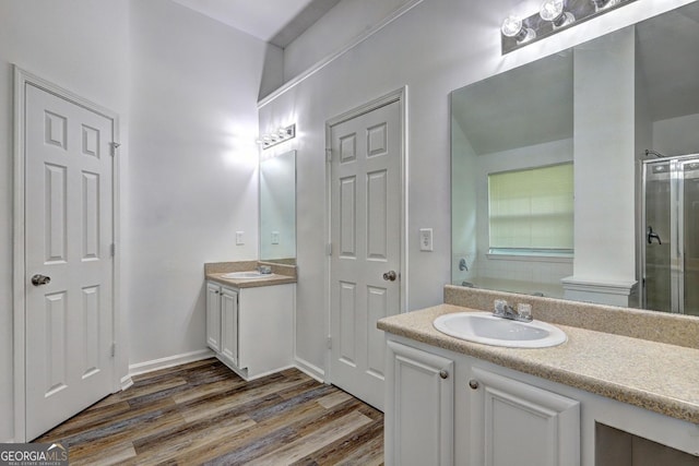 bathroom with wood finished floors, two vanities, and a stall shower