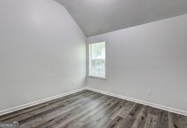 unfurnished room featuring lofted ceiling, dark wood-style flooring, and baseboards