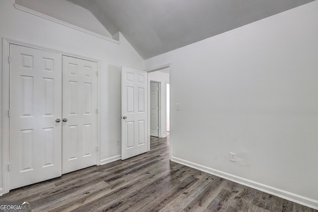 unfurnished bedroom featuring lofted ceiling, wood finished floors, a closet, and baseboards