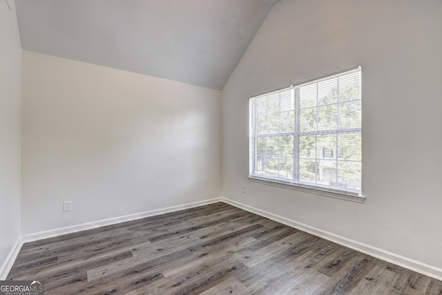 spare room with vaulted ceiling, dark wood-style floors, and baseboards