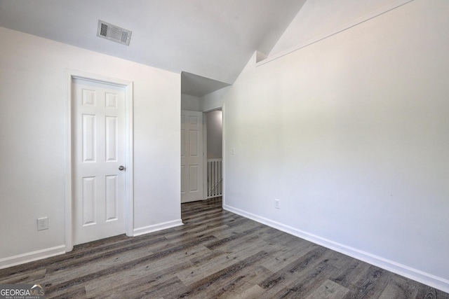 unfurnished bedroom with lofted ceiling, wood finished floors, and baseboards