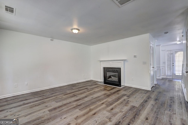 unfurnished living room with wood finished floors, a glass covered fireplace, and baseboards