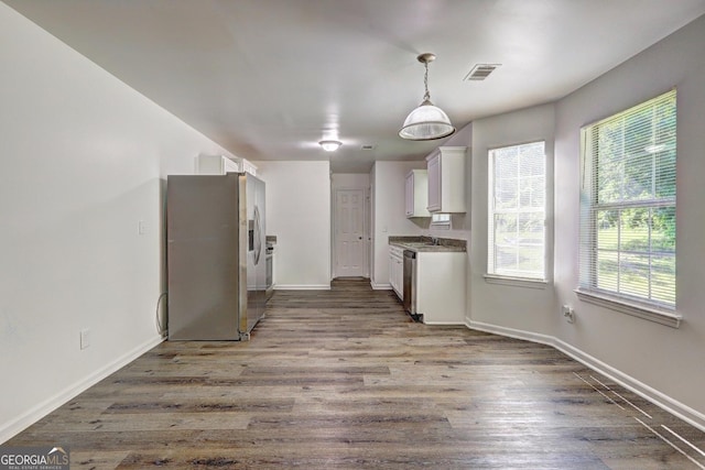 kitchen with stainless steel appliances, white cabinetry, wood finished floors, and baseboards